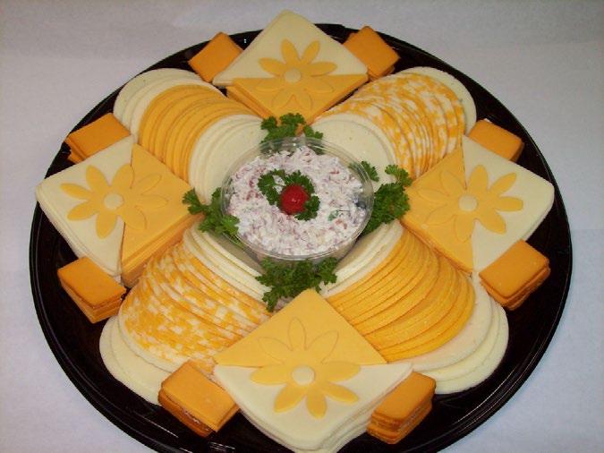 Cheese tray of sliced Colby, Kojack and baby Swiss with flower-cut squares around a bowl of ham salad spread